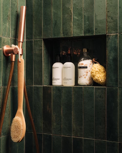 Eigentijdse badkamer met donker groene betegeling en rose gouden kraan