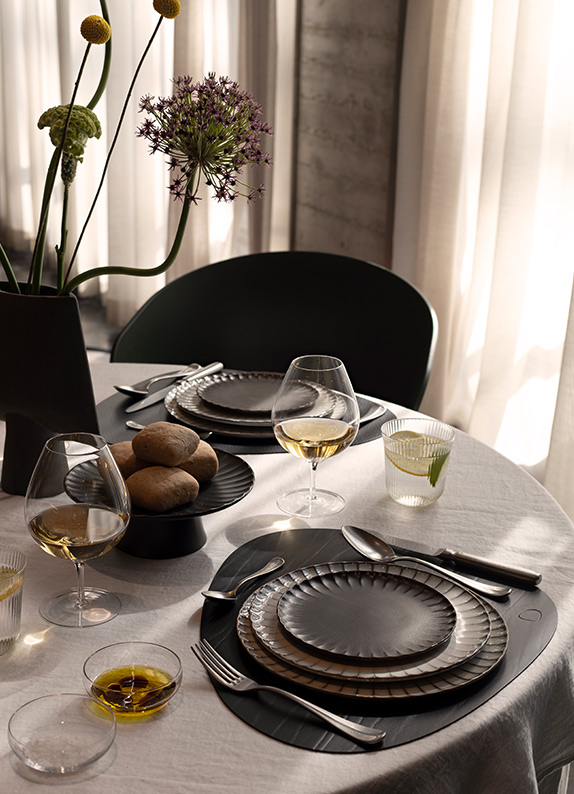 Uitgebreid gedekte tafel met wit tafellinnen en zwart servies