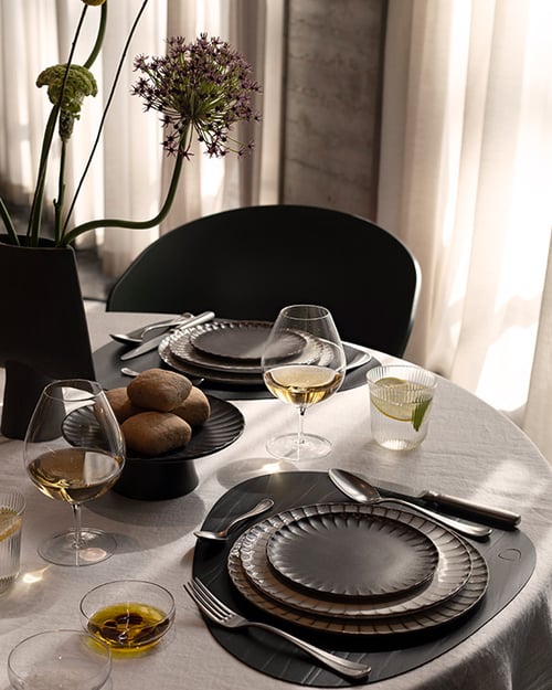 Uitgebreid gedekte tafel met wit tafellinnen en zwart servies